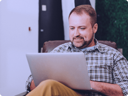 Homem sentado e usando um laptop.